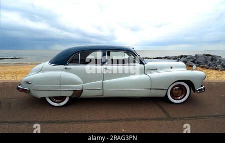 Vintage White Buick Special  Motor Car parked on seafront promenade beach and sea in background. Stock Photo