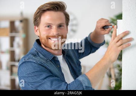 man hanging window curtain indoors Stock Photo