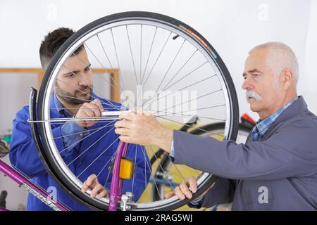 two bicycle repairer colleagues working in bike garage Stock Photo