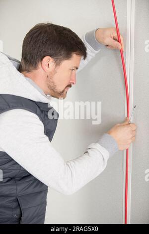 worker trying to install wires on the wall Stock Photo