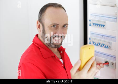 portrait of mature electrician testing fusebox with multimeter Stock Photo