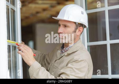 man measuring window prior to installation Stock Photo