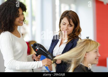 hairdressing apprentice ironing the clients hair Stock Photo