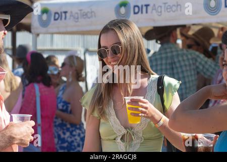 Young pretty caucasian smiling woman holding a drink on Ladies' Day at the Brunette Downs ABC Amateur Bush races, a traditional Outback event, Norther Stock Photo