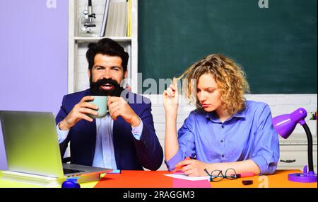 Students studying in university. Male teacher and female student in classroom. Male and female teachers working with laptop in auditorium. Sad female Stock Photo