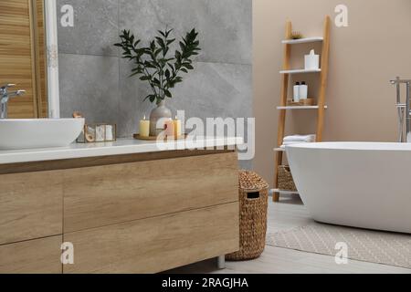 Beautiful plant in vase and burning candles near vessel sink on bathroom vanity Stock Photo