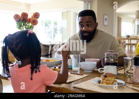 African american father talking with daughter while having breakfast at dining table at home Stock Photo
