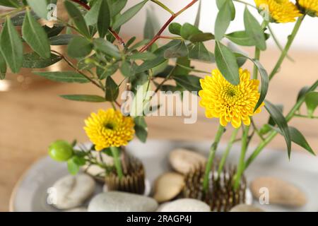 Ikebana - composition of flowers with yellow flowers and green leaves and  cereales and branch trunks on background of Japanese teahousewith specific  Stock Photo - Alamy