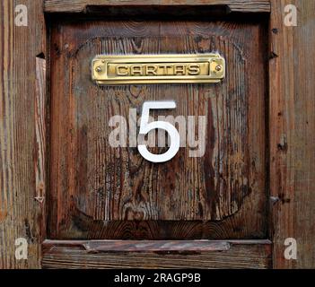 Door number 5, a grungy wooden panel with number five and a letter slot (Spanish: cartas, English: letters). Stock Photo