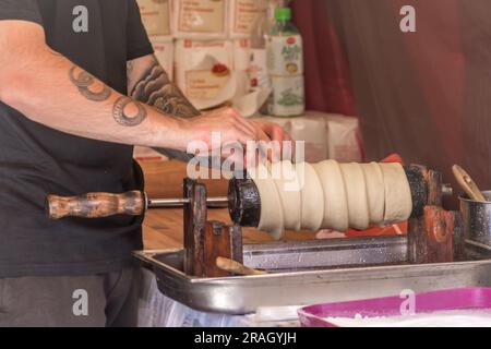 Raw chimney cake rolls popular street food prepared by a tattoo hand Stock Photo