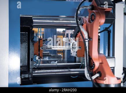 Automated manufacturing process. Robot arm remove finish products on injection molding machine. Stock Photo