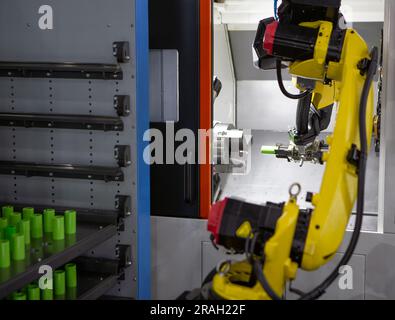 Automated manufacturing process. Robot arm loading workpieces on CNC lathe machine. Stock Photo