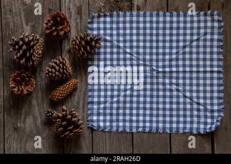 a blue napkin in a cage lies on a wooden table and next to cones from a Christmas tree, table decoration Stock Photo