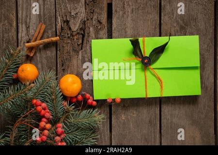 pine branch and viburnum and green envelope with a gift lie on an old wooden background, New Year's decor Stock Photo