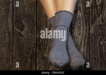 female legs in blue socks on wooden background close up Stock Photo