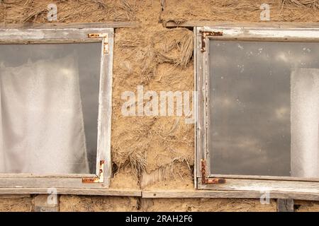 window on an old wall of a house made of clay in the countryside in Ukraine Stock Photo