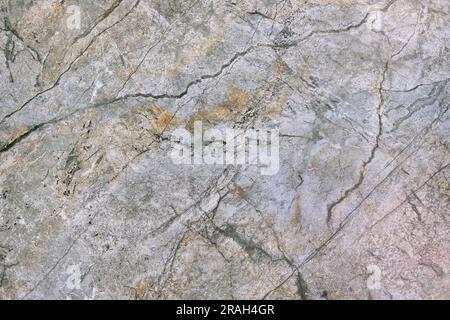 Stone textural granite polished surface of a gray-green hue with various stripes, cracks and inclusions. Stock Photo