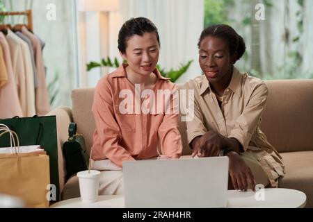 Diverse friends sitting on couch at home and making purchases in online shop Stock Photo