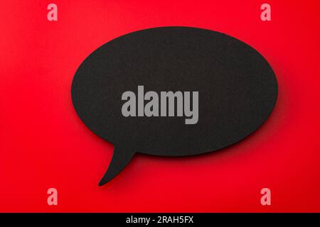 Black Cardboard Cutout of Blank Speech Bubble on Red Background with Copy Space: Concept for Dialogue Design Elements, Expressing Communication Symbol Stock Photo
