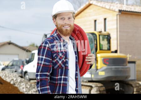 happy worker moving pipes outdoors Stock Photo