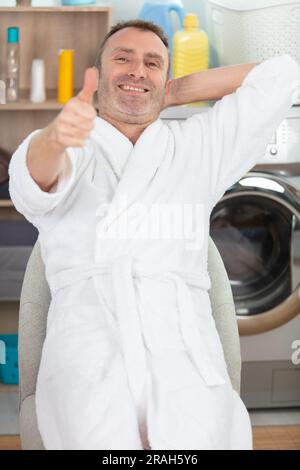 man in utility room wearing dressing gown showing thumbs up Stock Photo