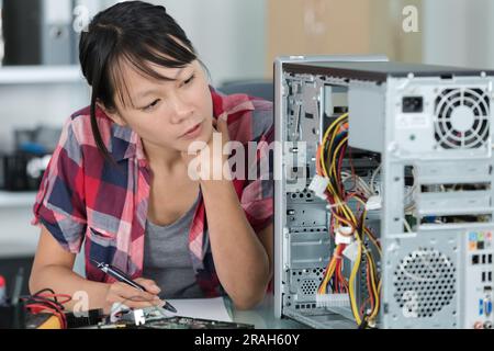 young female student fixing a pc components in classroom Stock Photo