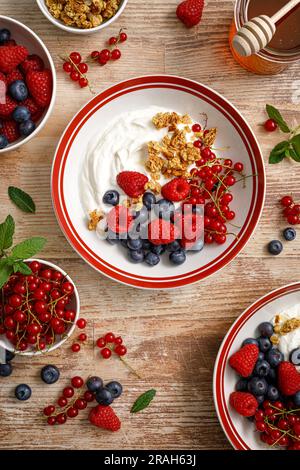 Yogurt with berries on wooden background. White plain greek yogurt with fresh berries and granola, top view. Healthy food, breakfast menu Stock Photo