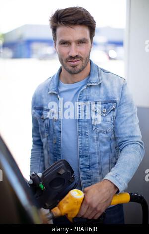 man filling gasoline fuel in car holding nozzle Stock Photo