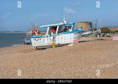 Two fishermen unloading their catch from a boat on a shingle beach Stock Photo