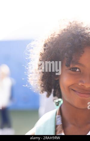 Vertical half face portrait of smiling african american elementary schoolboy outdoors, copy space. Education, inclusivity, elementary school and learn Stock Photo