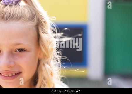 Half face portrait of smiling cauasian elementary schoolgirl in school ...