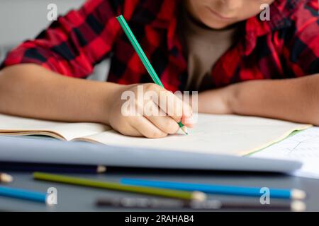 Midsection of caucasian schoolboy sitting at desk writing in class concentrating. Education, childhood, elementary school and learning concept. Stock Photo
