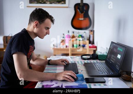Young man software developer working from home on his laptop Stock Photo