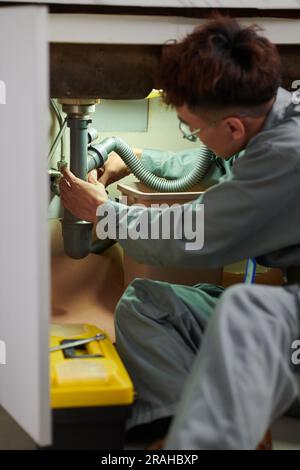 Plumber unclogging kitchen sink, household service Stock Photo