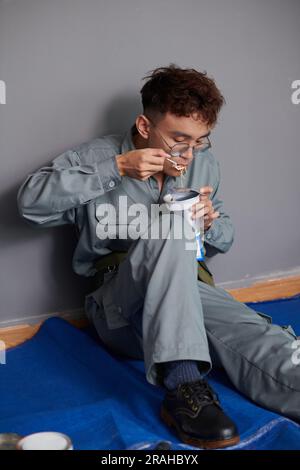 Hungry builder having instant noodles when eating lunch at construction site Stock Photo