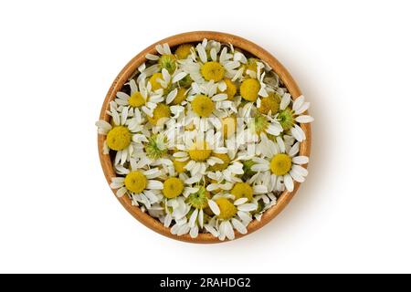 Chamomile flowers in wooden bowl on white background Stock Photo