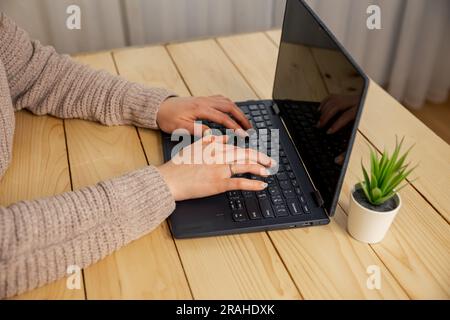 Woman using the laptop at home. Woman typing on laptop keyboard. Stock Photo