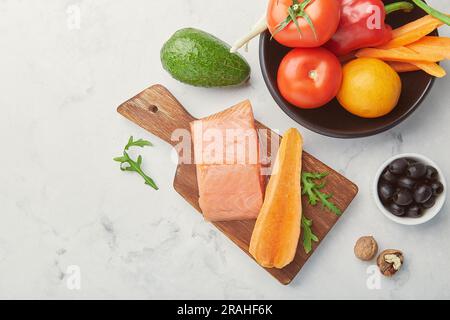 Keto, Low carb, FODMAP diet food with vegetables and fruits, smoked salmon, greens, nuts, olives. Healthy eating. Stock Photo