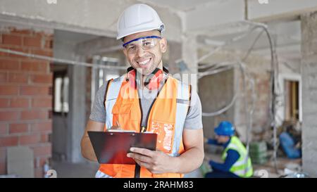 Two men builders writing document working at construction site Stock Photo