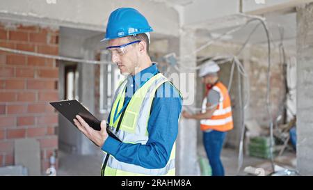 Two men builders writing document working at construction site Stock Photo