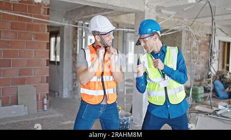 Two men builders smiling confident dancing at construction site Stock Photo
