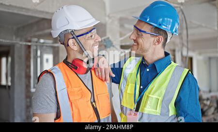 Two men builders smiling confident standing together at construction site Stock Photo