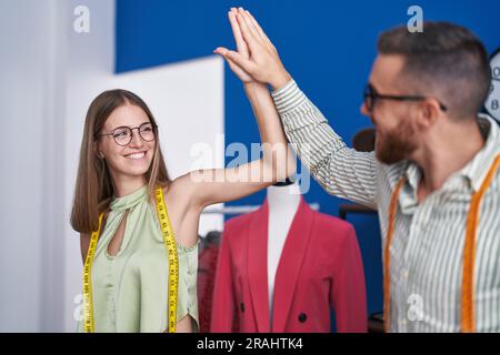 Man and woman tailors high five with hands raised up at clothing factory Stock Photo