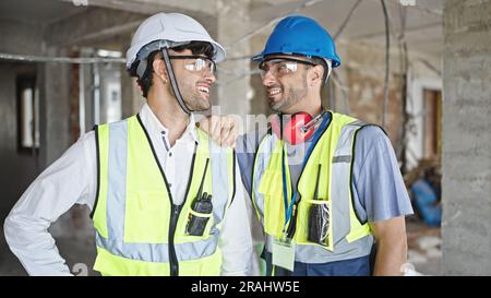 Two men builders smiling confident standing at construction site Stock Photo