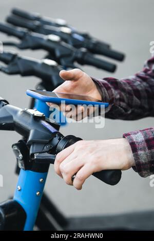 Close up of man hand using mobile app for rental electric scooter. Stock Photo