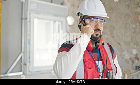 Young latin man builder talking on smartphone at construction site Stock Photo