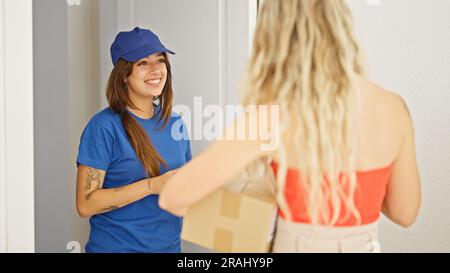 Young beautiful hispanic woman delivery woman giving package to client at home Stock Photo