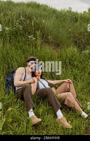 Fashionable romantic couple in newsboy caps and suspenders holding ...