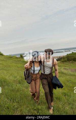 Fashionable romantic couple in newsboy caps and suspenders holding ...