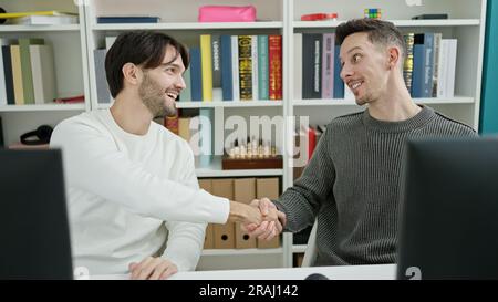 Two men students shake hands studying at library university Stock Photo